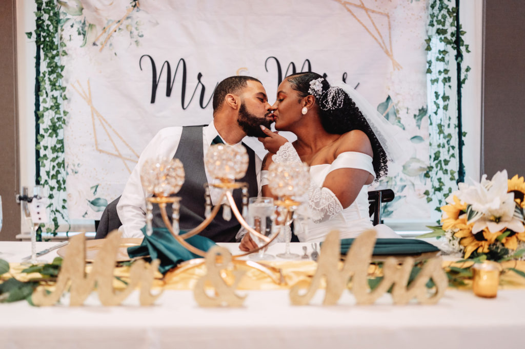 bride and groom kissing at their sweetheart table during their wedding reception