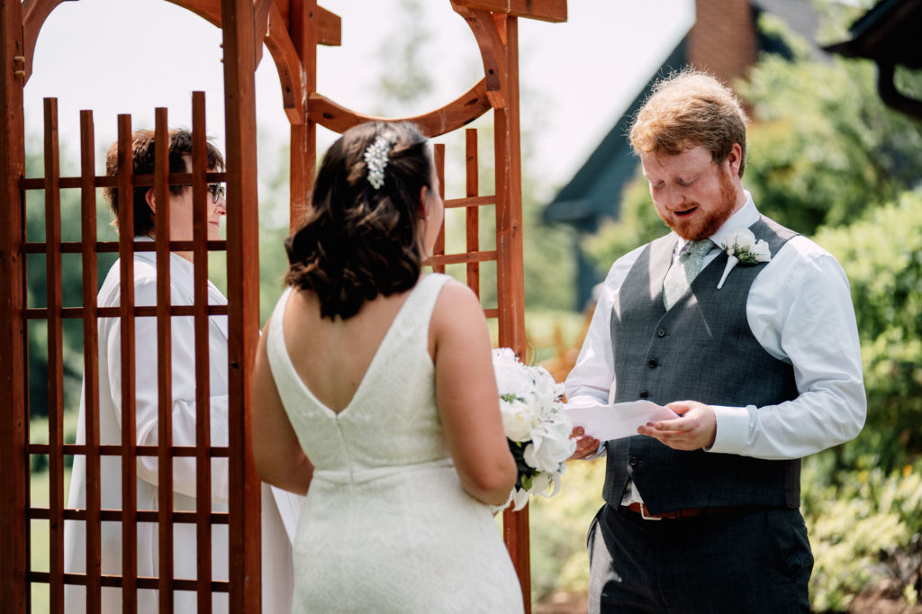 groom reading personalized vows to his bride during their wedding ceremony