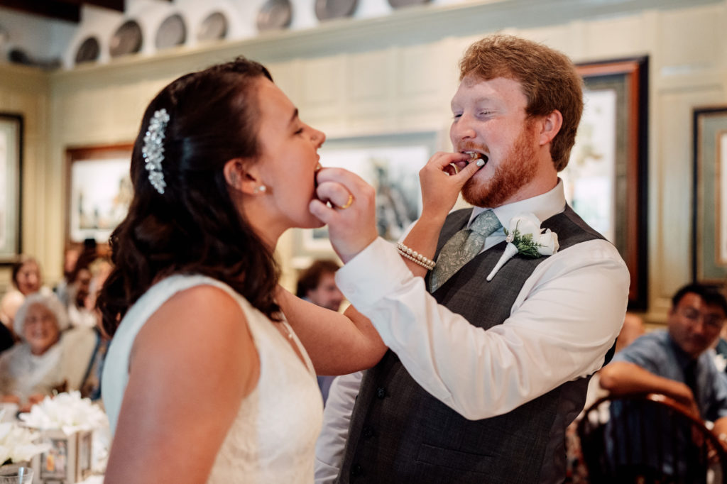 bride and groom feeding each other cake during their wedding reception
