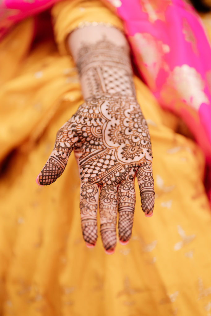 bride shows hand covered in mehndi