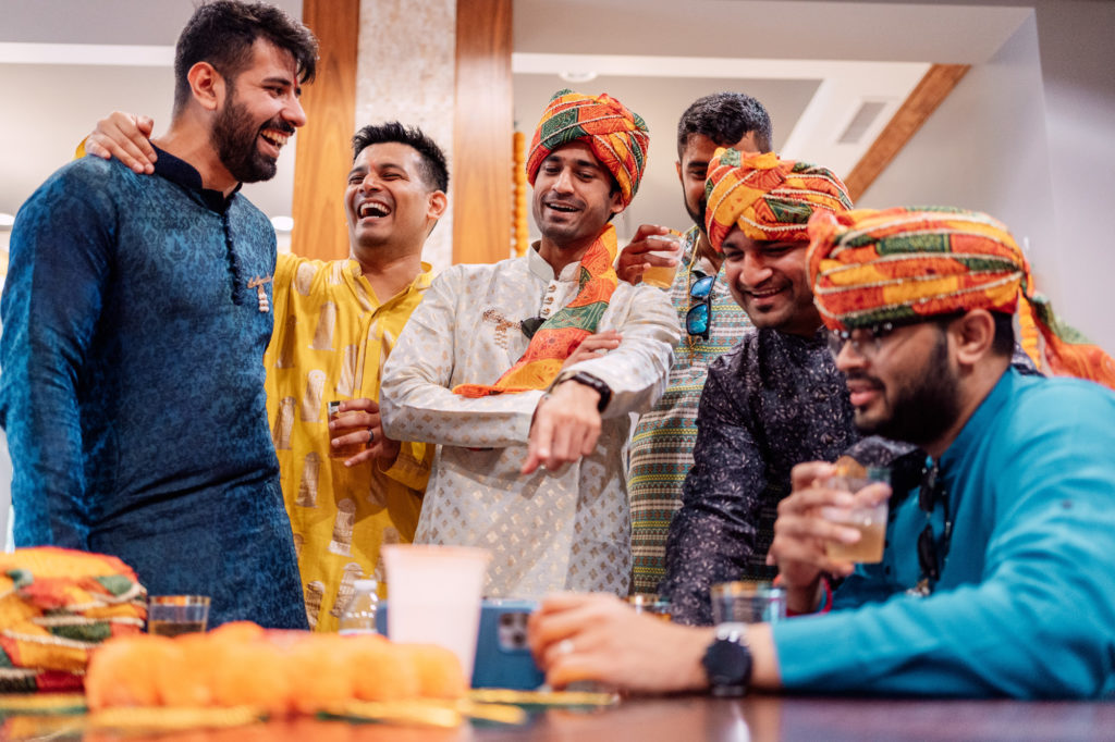 groom and friends laughing while reviewing dance videos