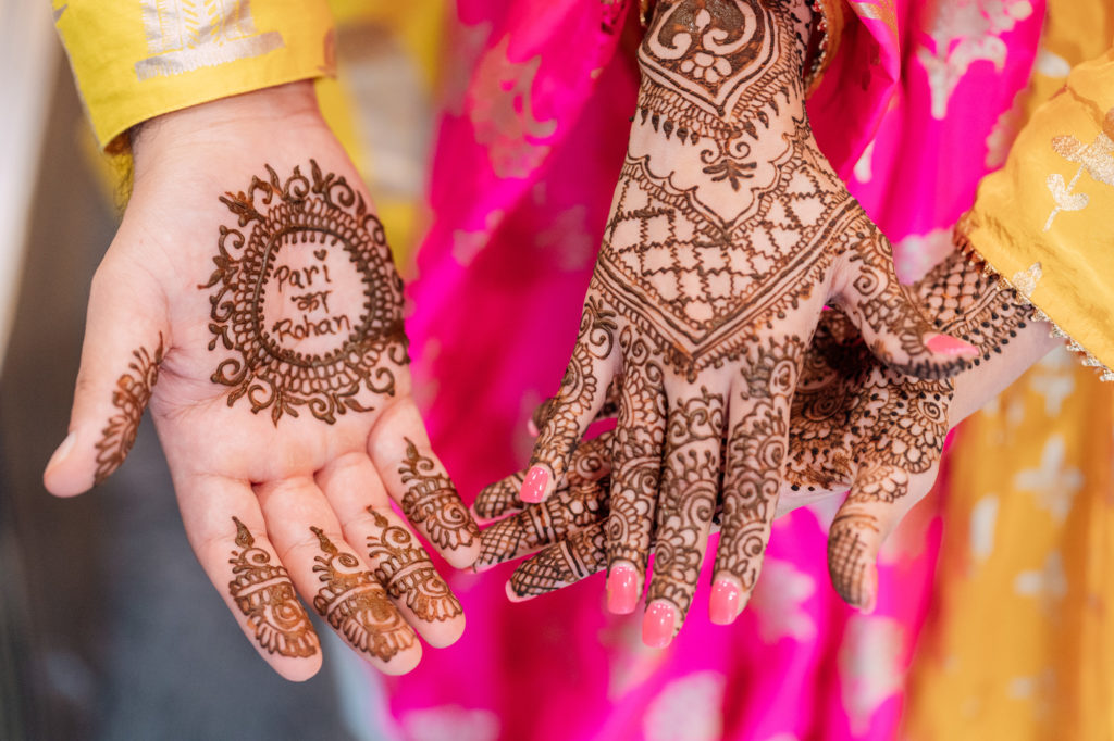 bride and groom show off their mehndi design for the camera