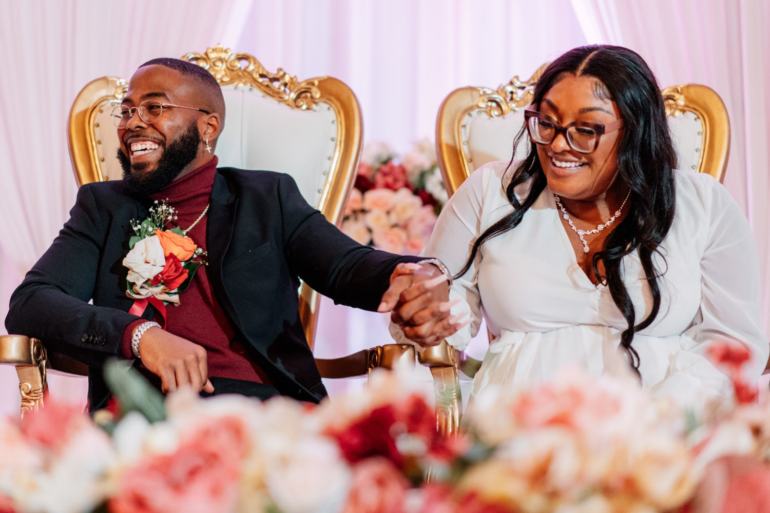 bride and groom laughing together while the groom's best man gives a speech