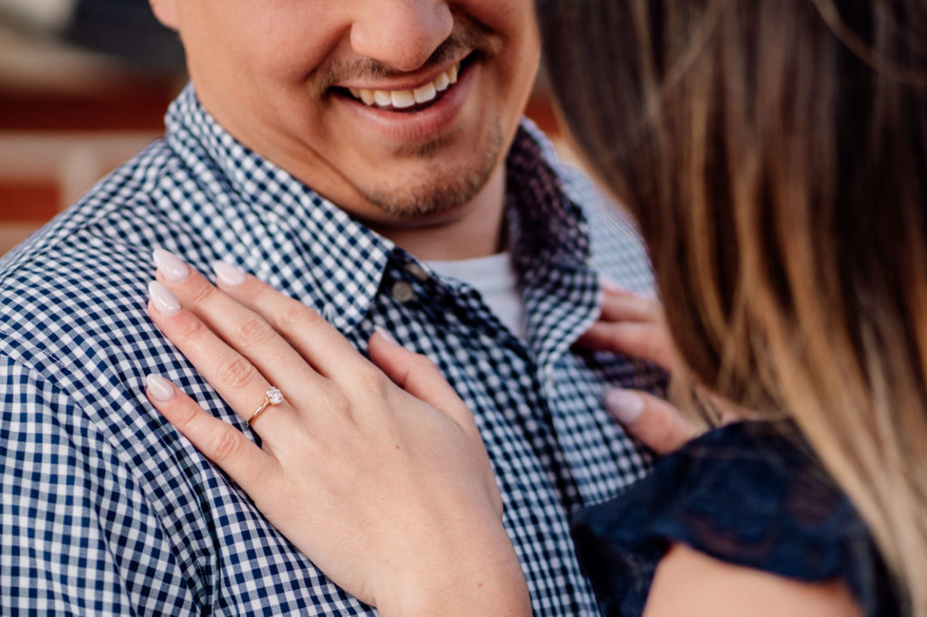couple interacting while bride shows off engagement ring
