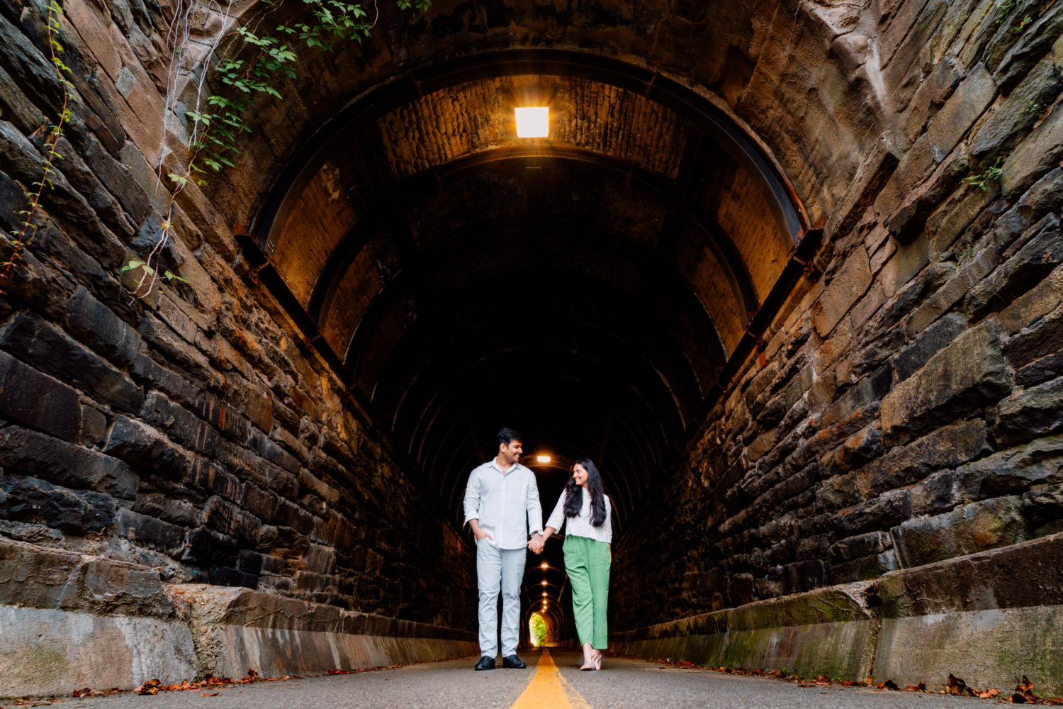 couple holding hands walking under wilkes tunnel at old town alexandria