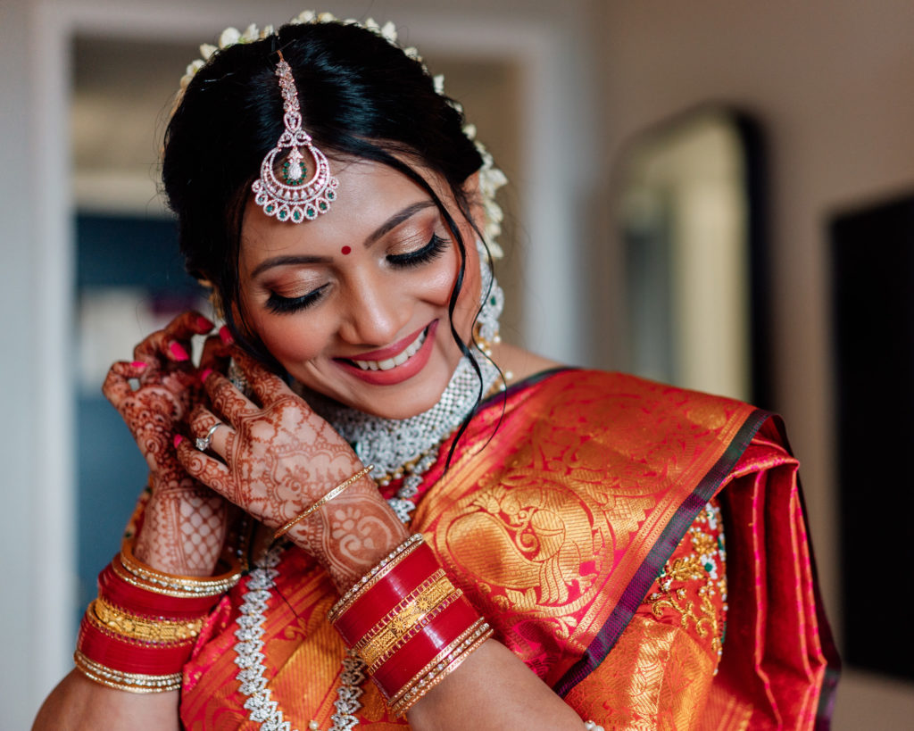 indian bride adjusting her earing and smiling