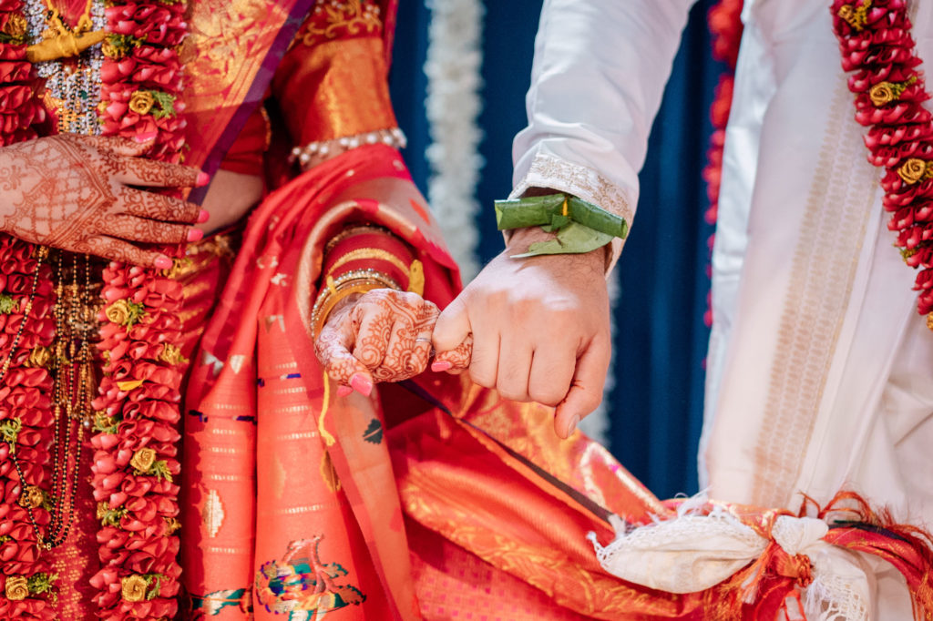 bride and groom wrapping pinky fingers during their indian wedding ceremony