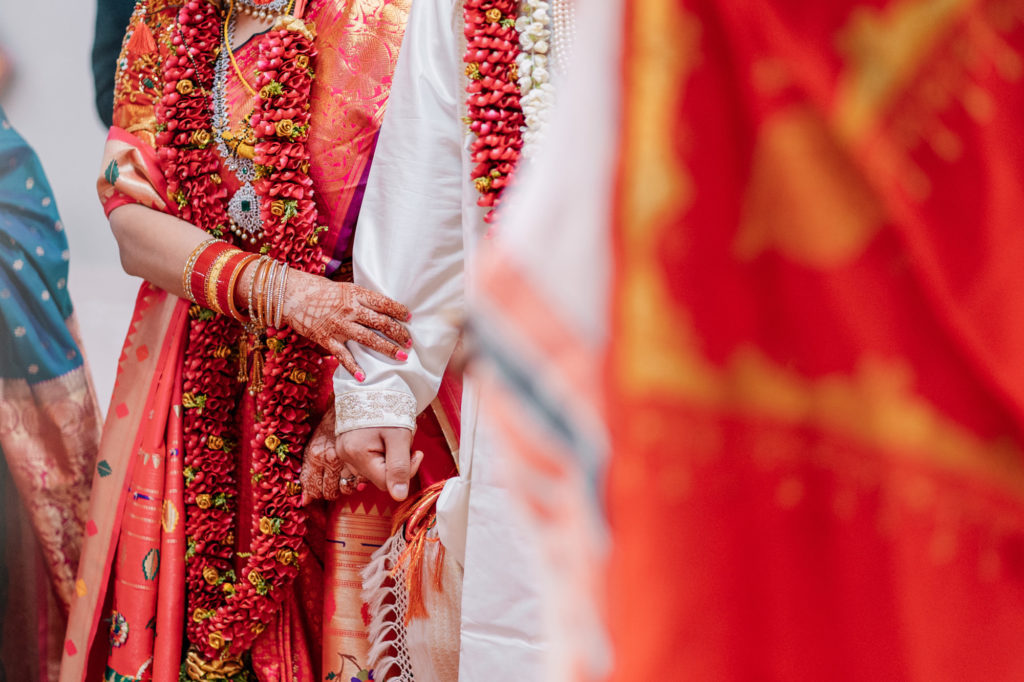 bride and groom holding hands during their indian wedding ceremony
