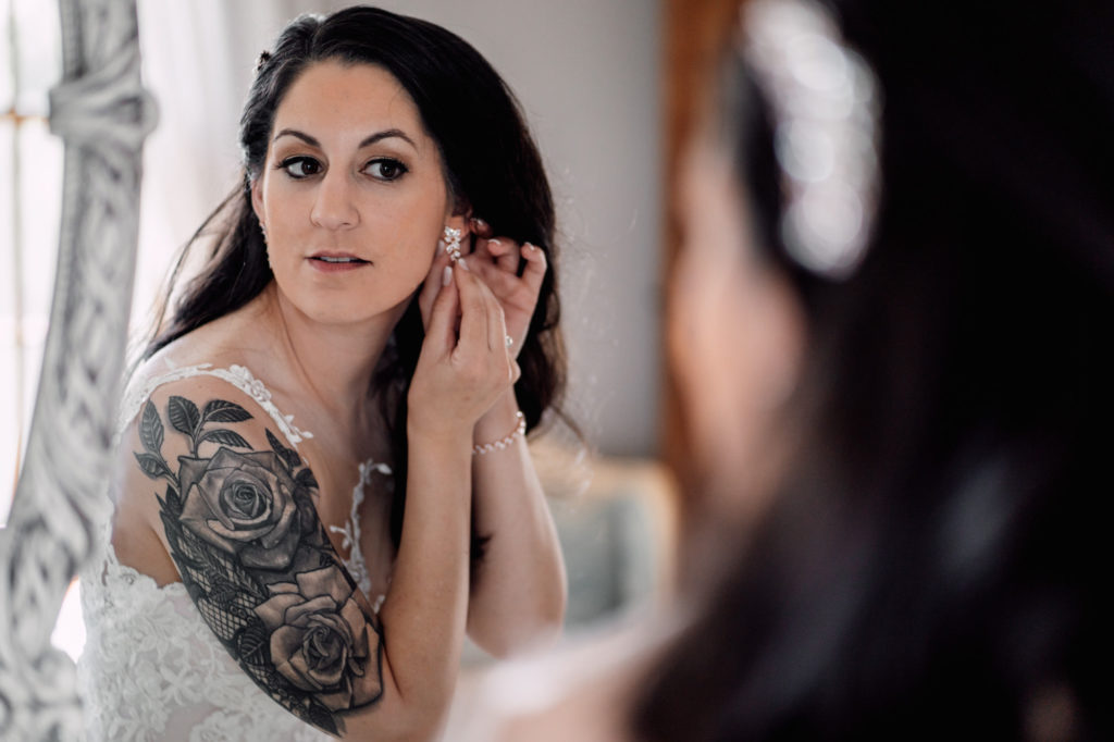 bride putting her earrings on while getting ready for wedding day