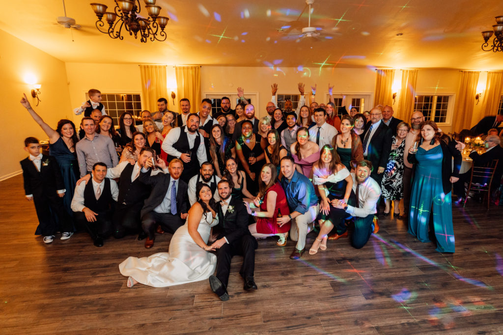 bride and groom take a large group photo with friends and family during their wedding reception