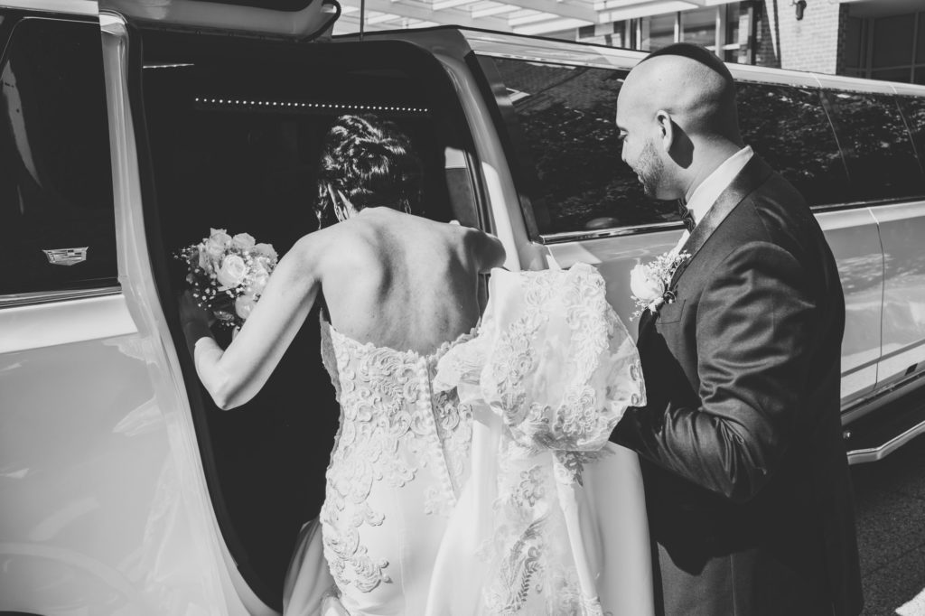 groom helping bride get into a limo