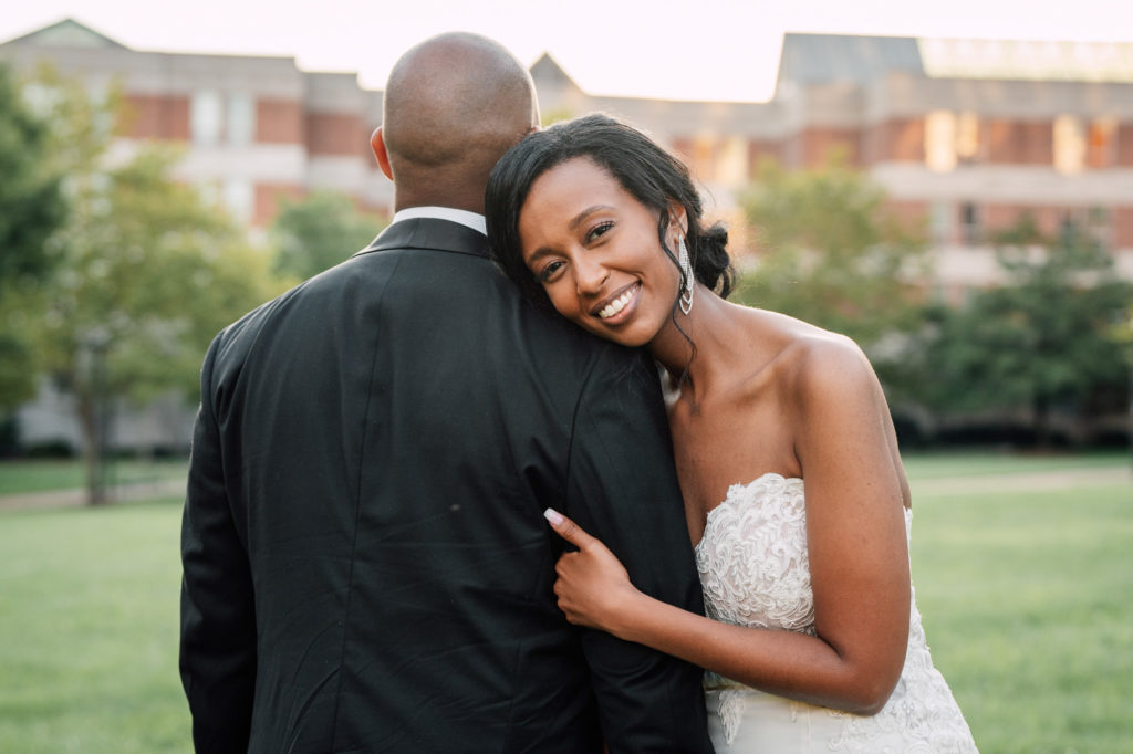 bride smiling at camera while hugging the groom's arm