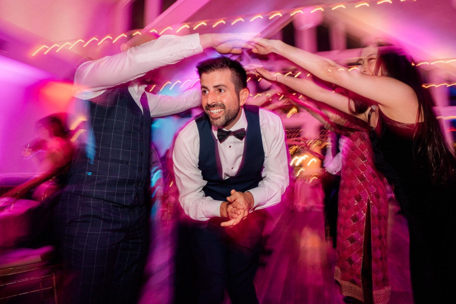 groom having fun during wedding reception dancing with friends