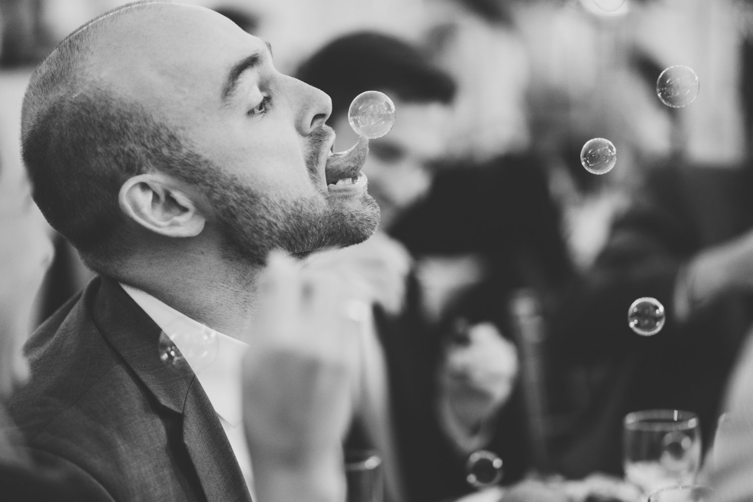 wedding guest sticking tongue out to pop bubble during wedding reception
