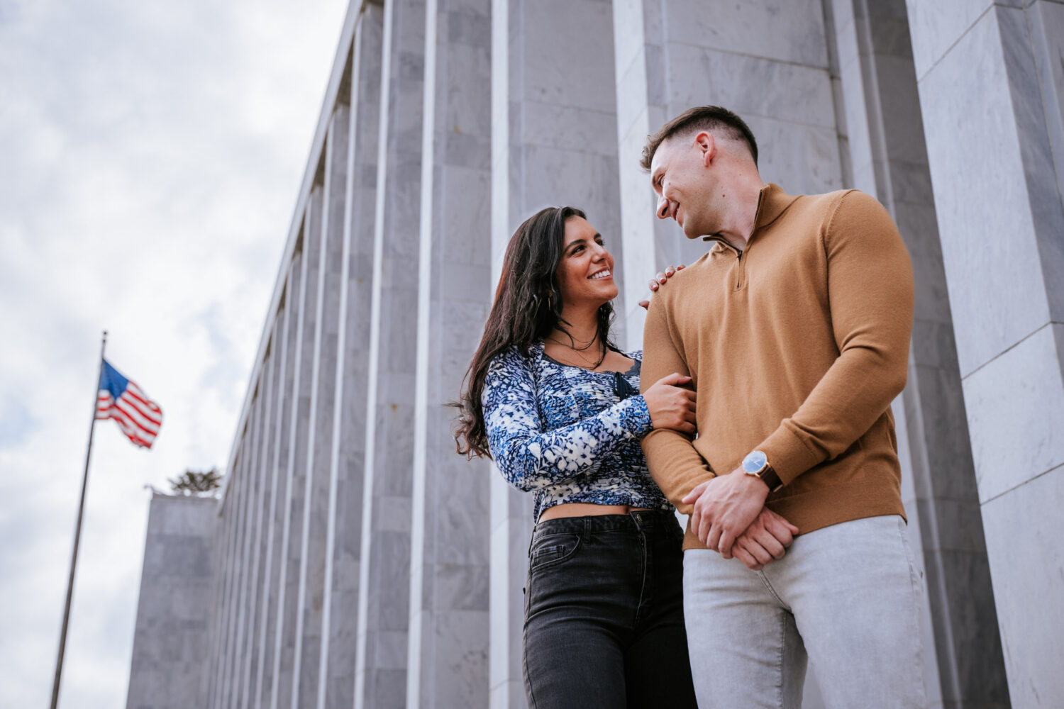 couple looking at each other and smiling with an American flag in the background