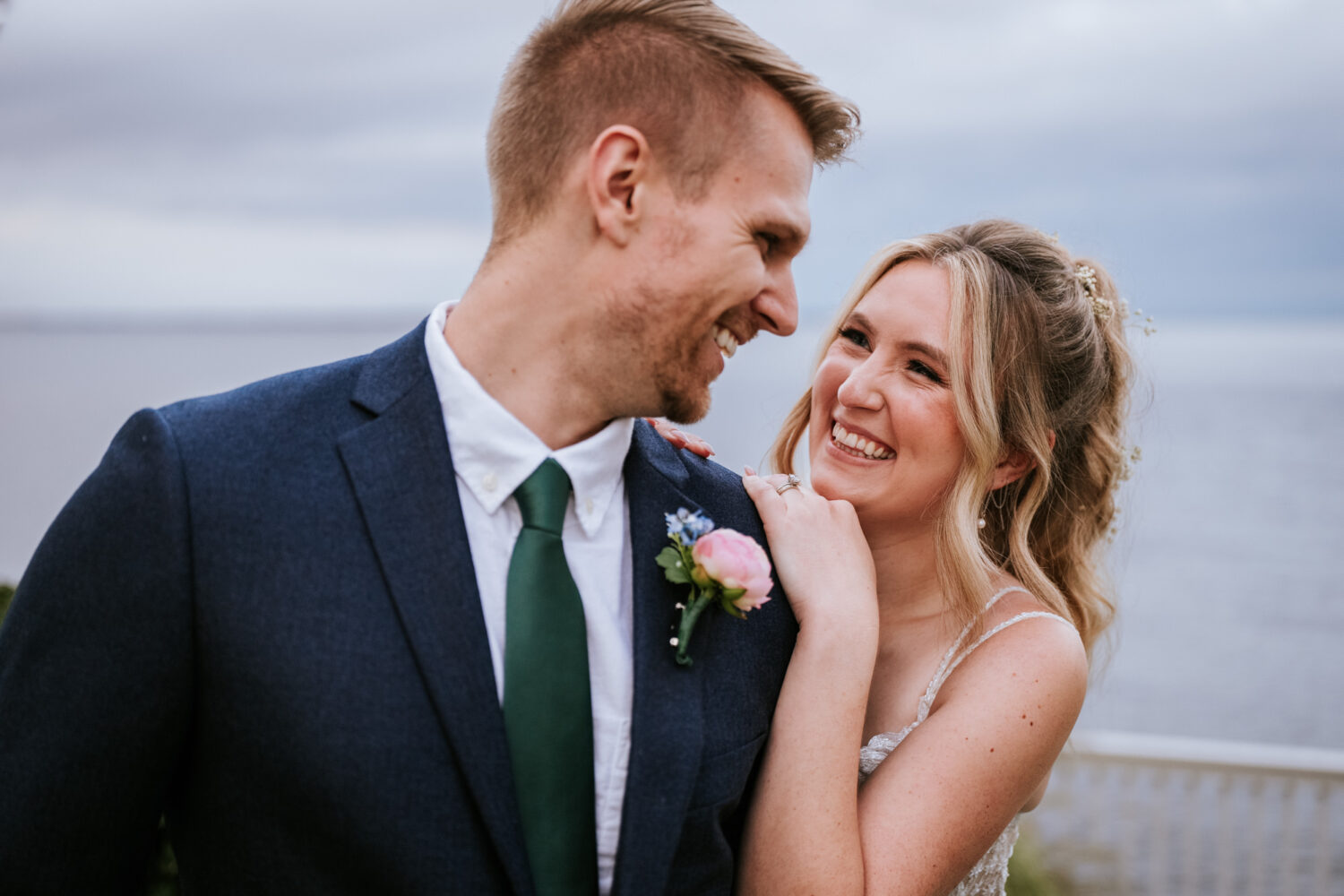 bride and groom laughing together by the water on their waterfront wedding day