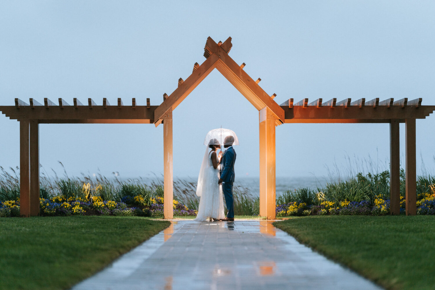bride and groom portrait under an arch during the rain on their herrington on the bay wedding day