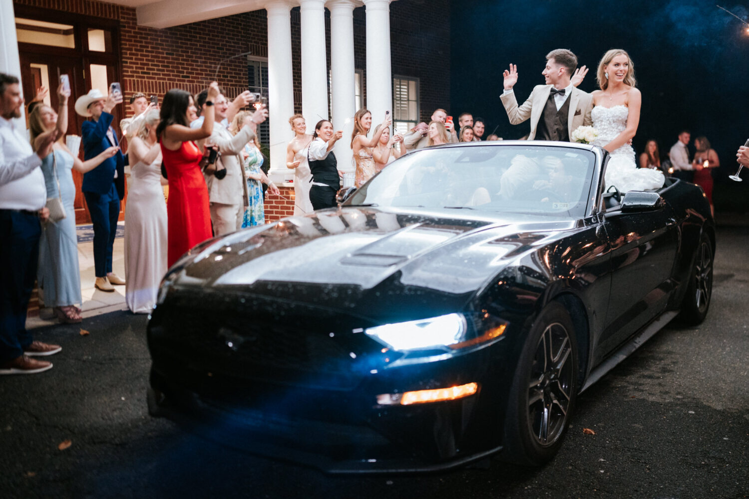 bride and groom exit their wedding day on a mustang 