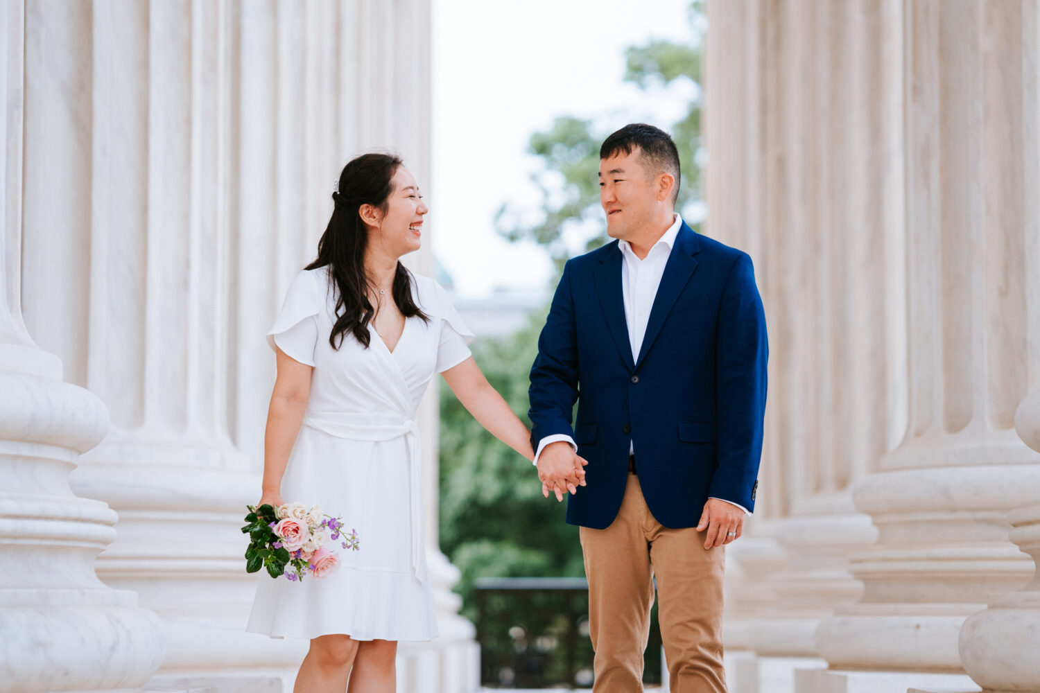 bride and groom walking together by the columns at the us supreme court