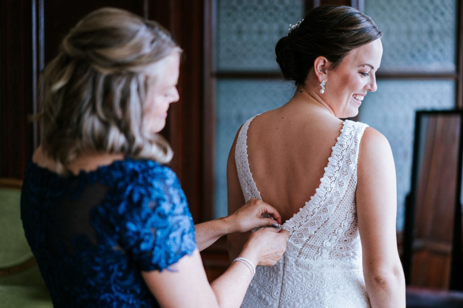 bride getting her dress put on by her mother