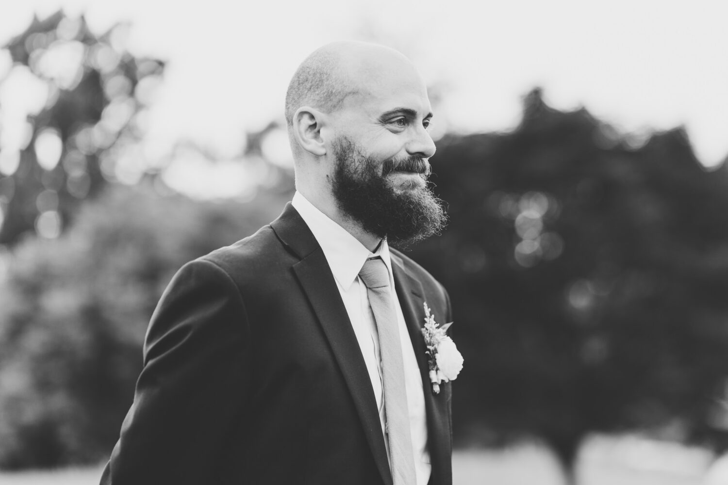 groom smiling while watching bride walk down the aisle