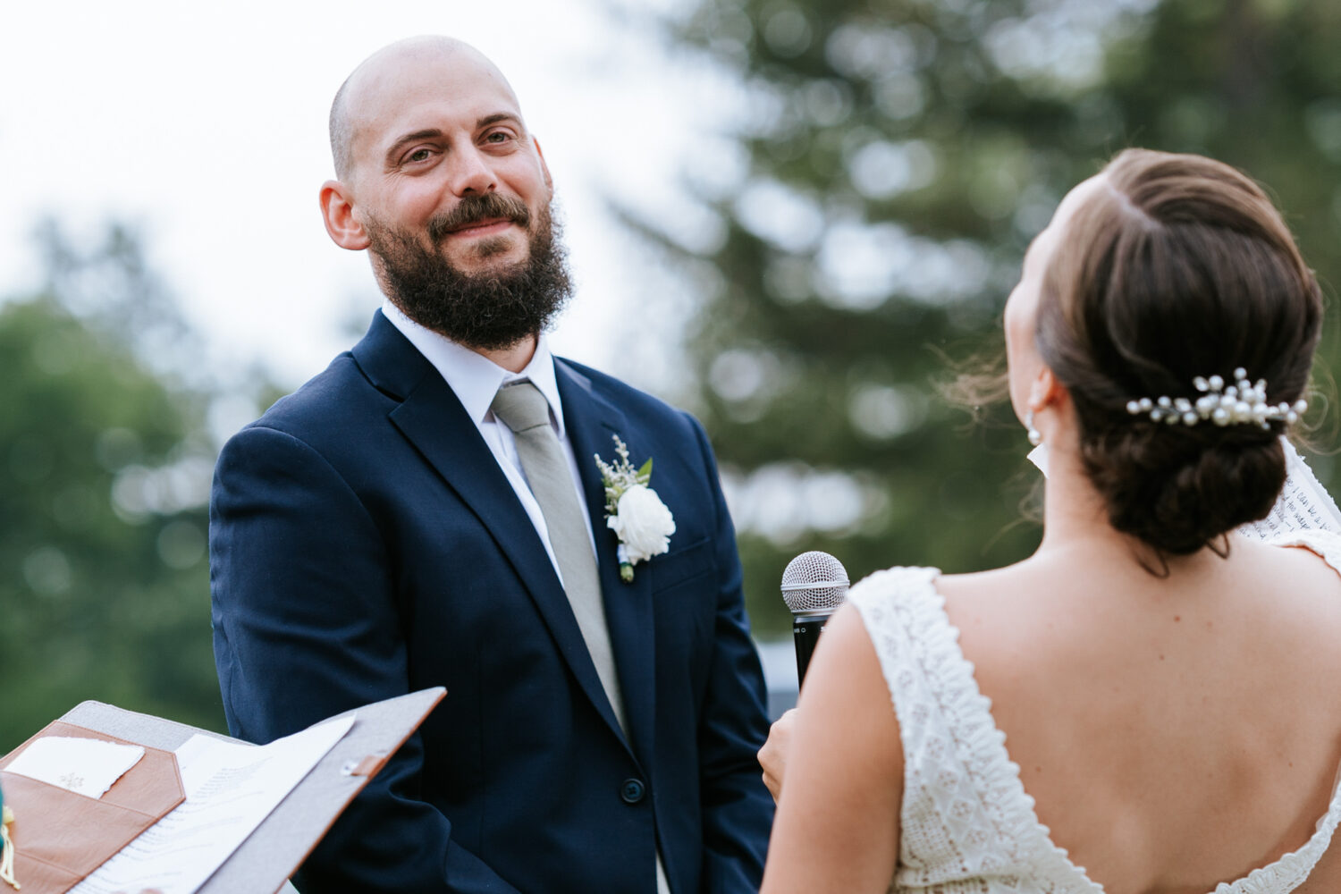 groom smiling while listening to bride read her vows
