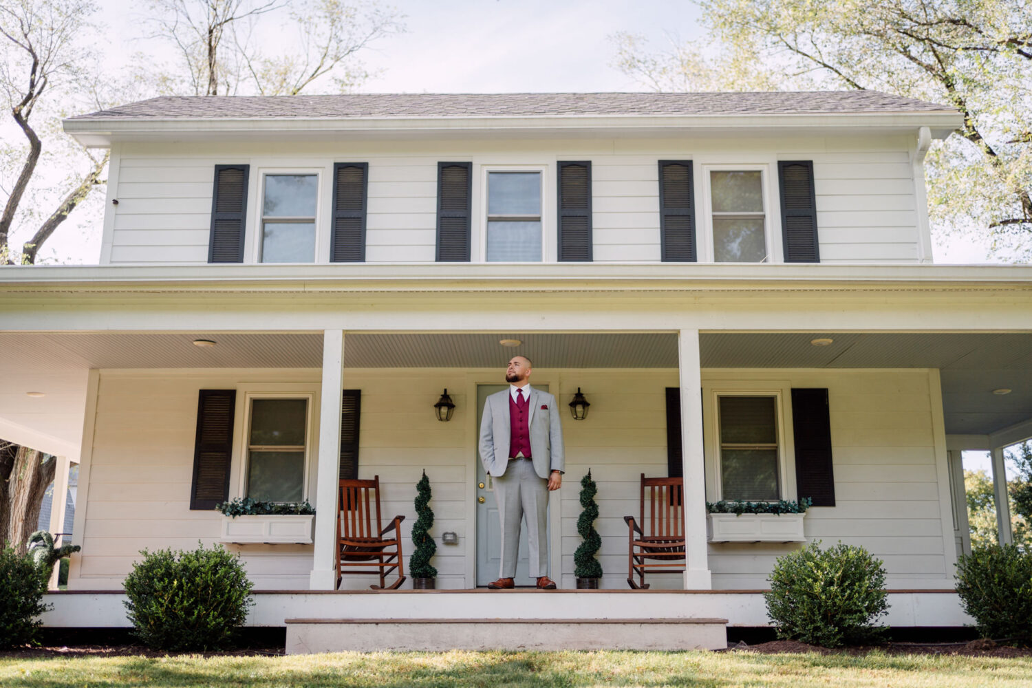 groom waiting on the outside of a house fully dressed for his wedding day
