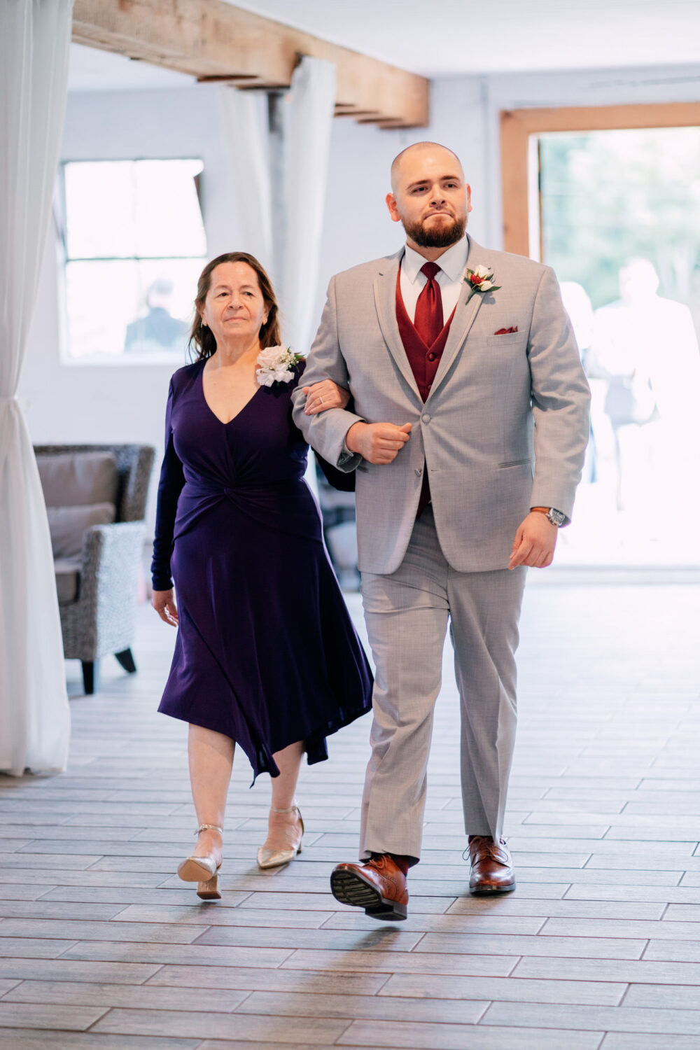 groom walking down the aisle with his mother