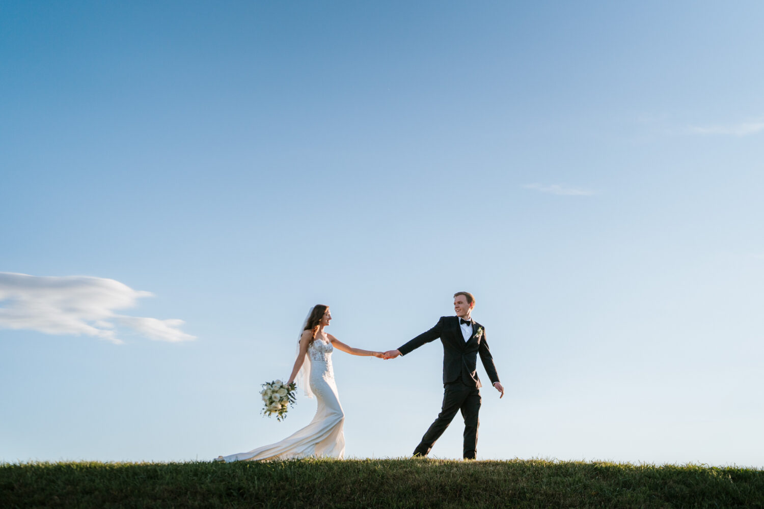 bride and groom walking together on top of a hill on their middleburg barn wedding day