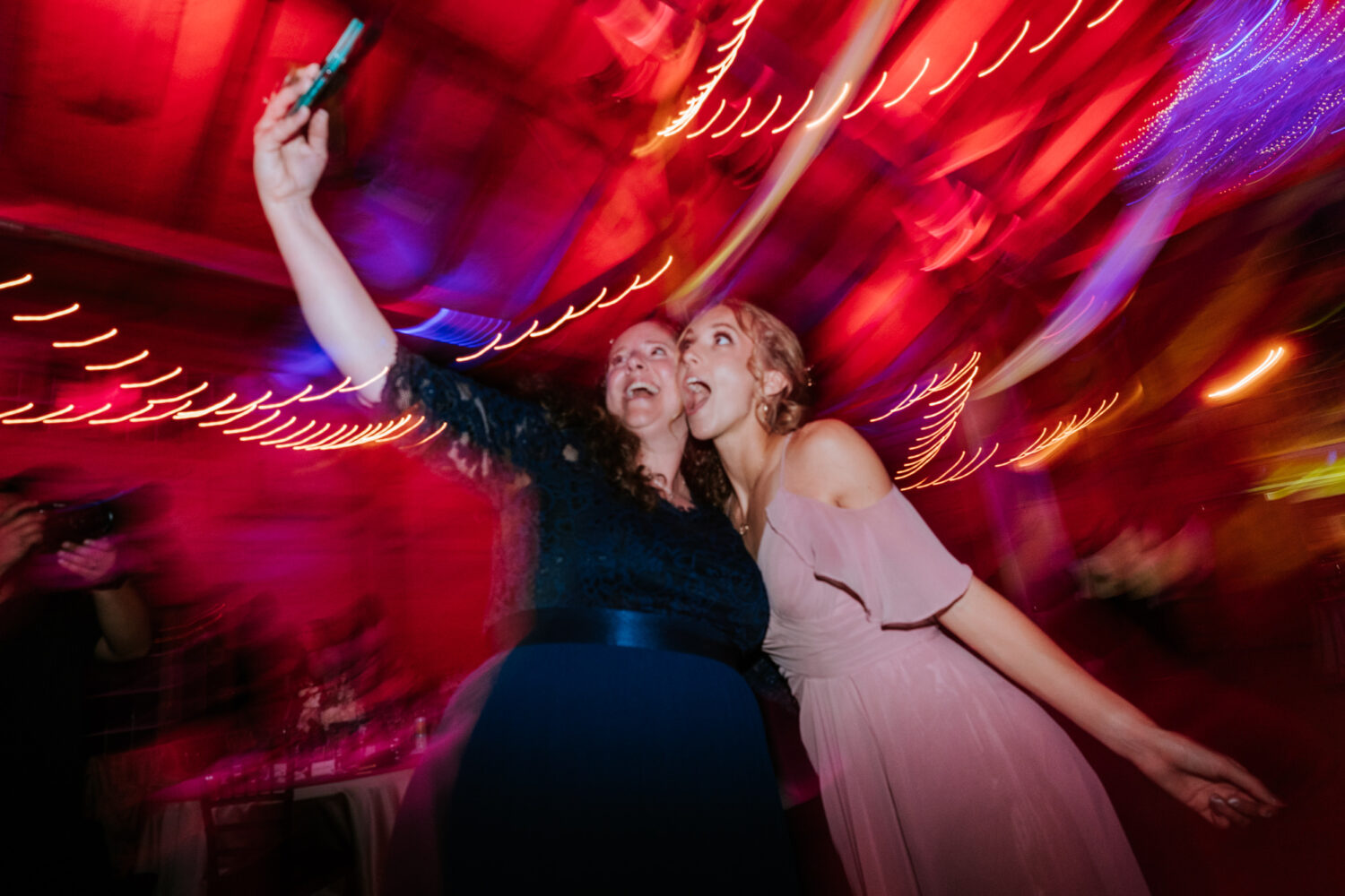 bridesmaid and guest taking a selfie together on the dance floor