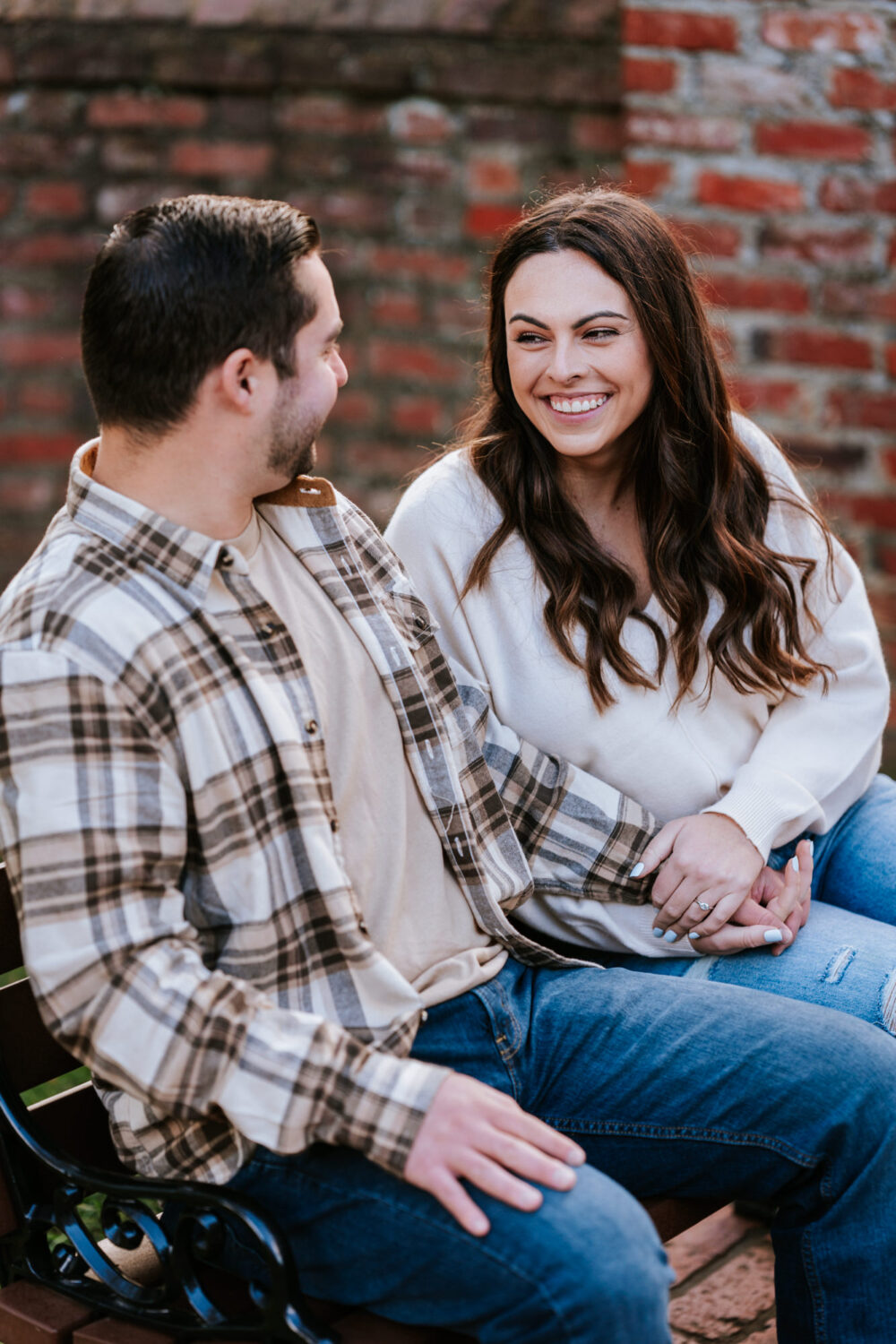girl looking at her fiance and smiling while they sit on a bench together