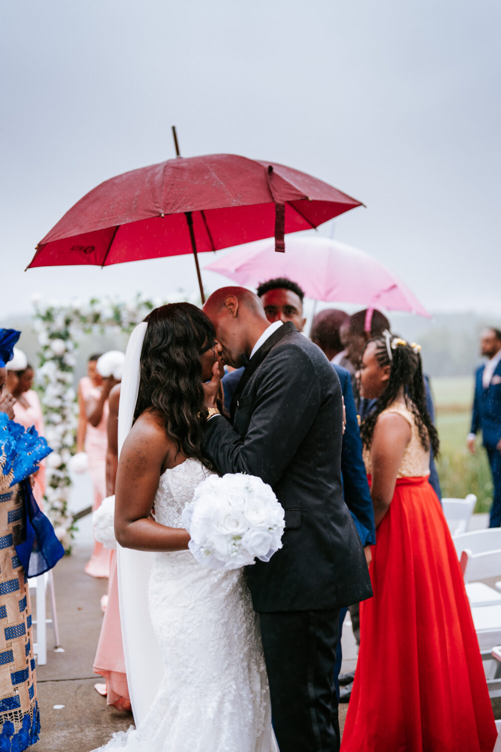 bride and groom share their first kiss in the rain on their wedding day