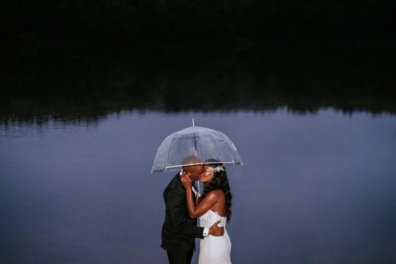 bride and groom share a final kiss in the rain on their riverside on the potomac wedding day