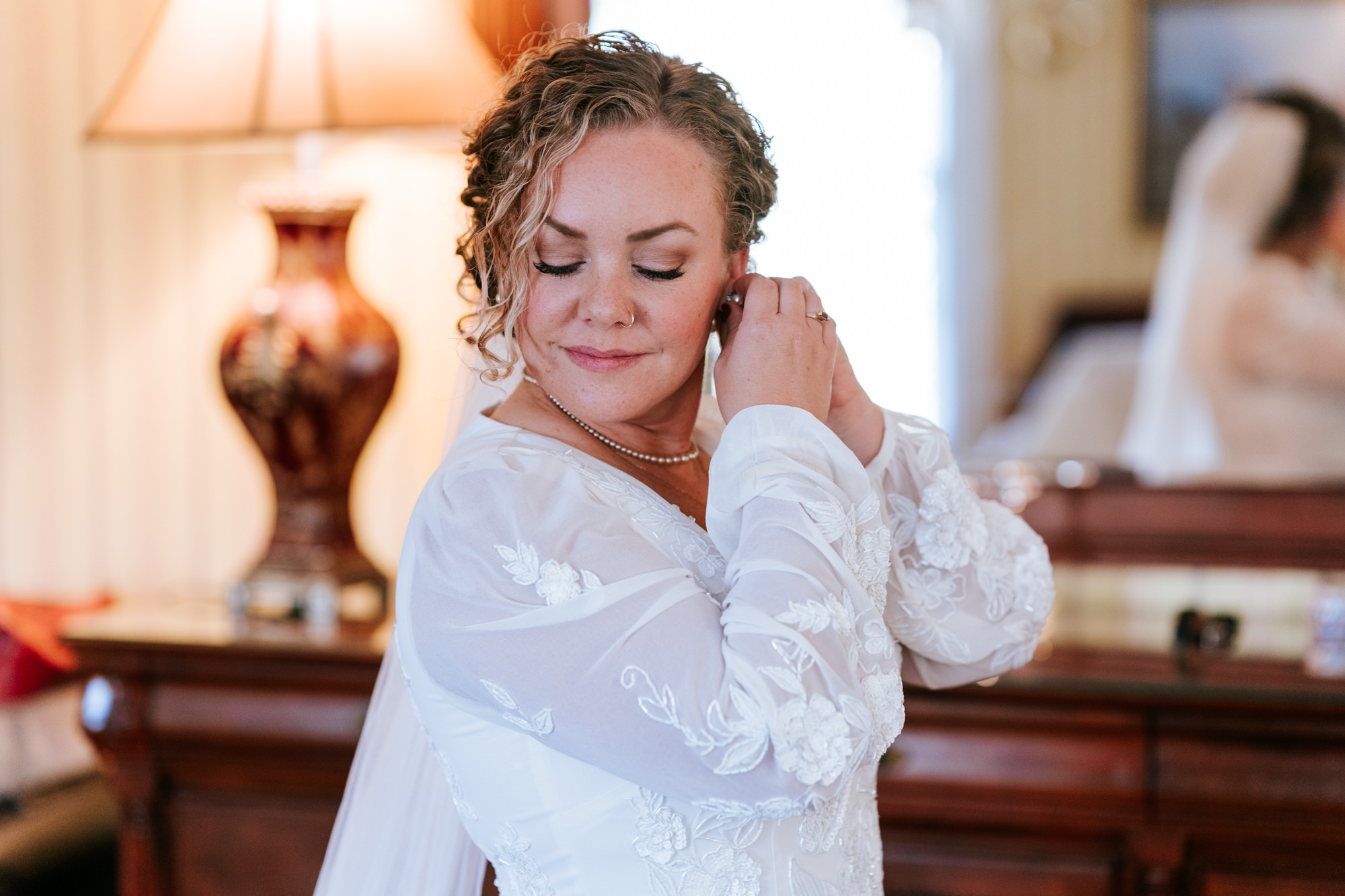 bride adjusting her earring while getting ready for her wedding day