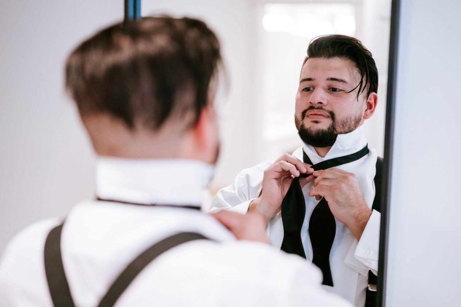 groom adjusting his tie before his wedding day begins