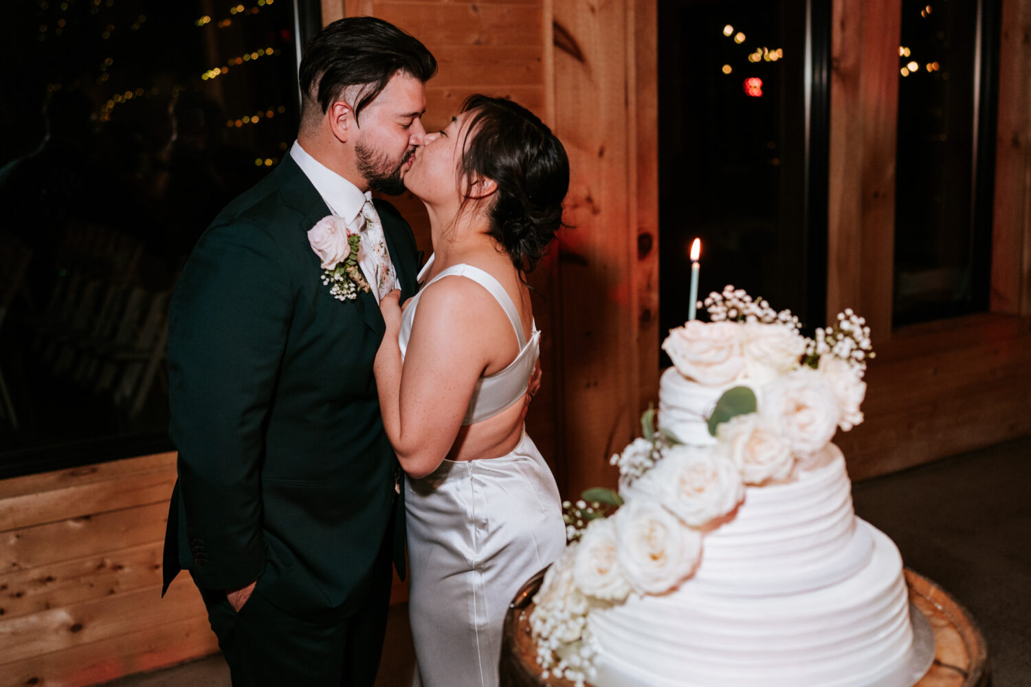 bride and groom kissing in front of their wedding cake