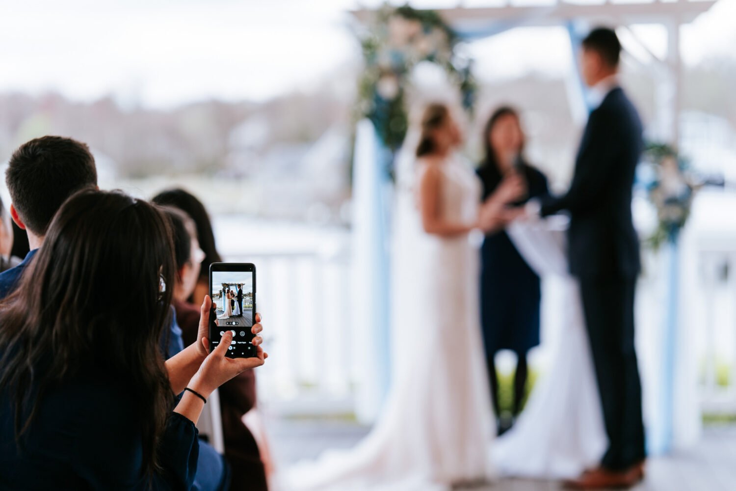 guest taking iphone picture of bride and groom at the altar