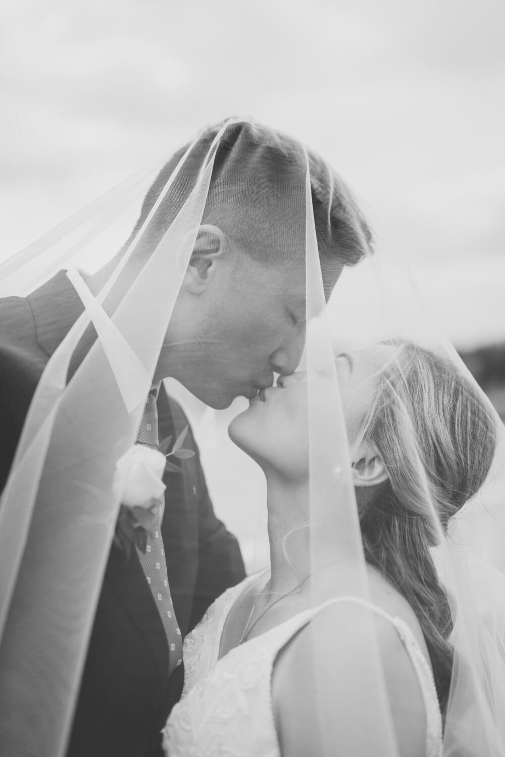 bride and groom kissing underneath a veil on their wedding day at anchor inn