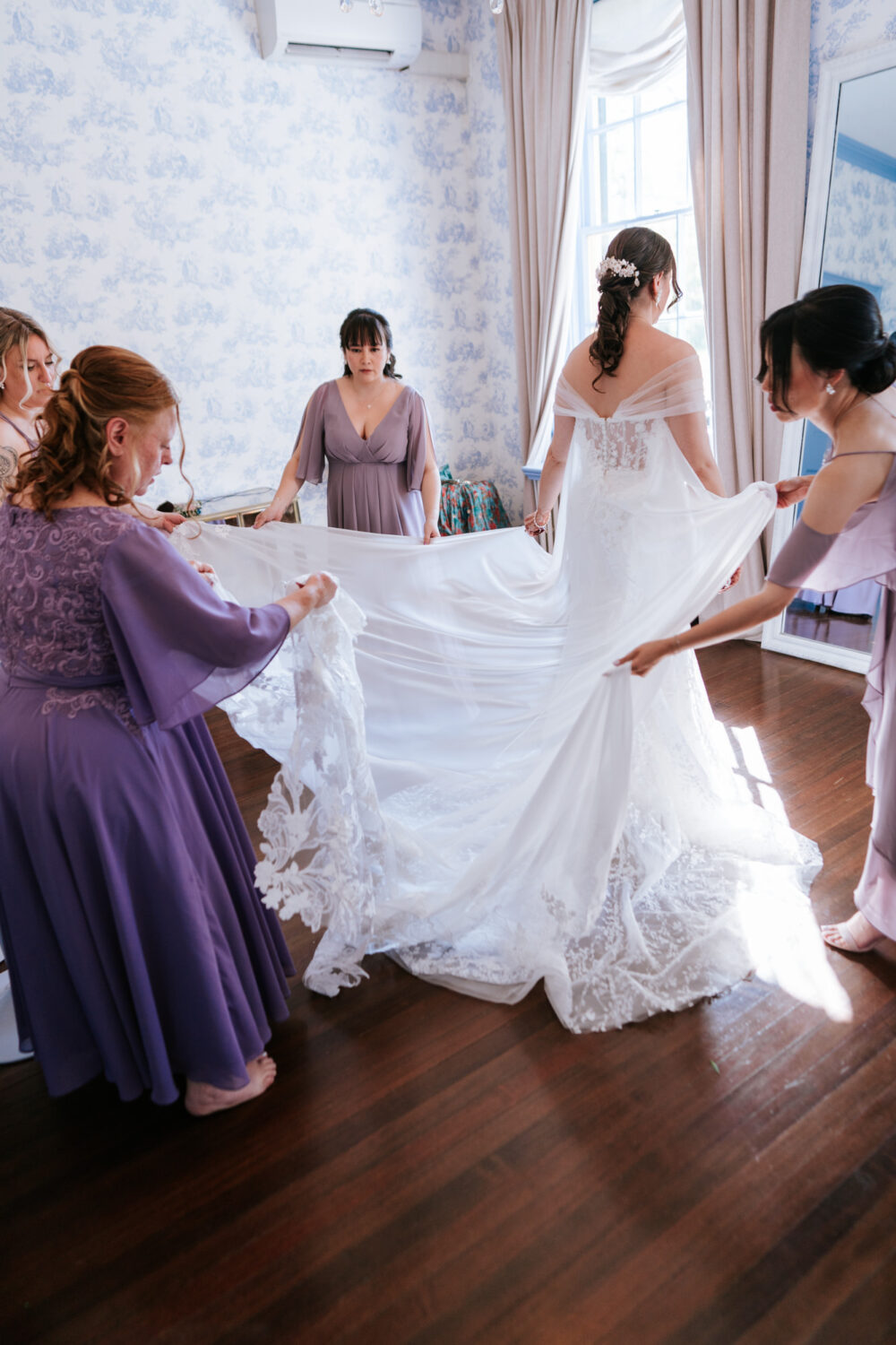 bridesmaids helping bride get ready in her wedding dress