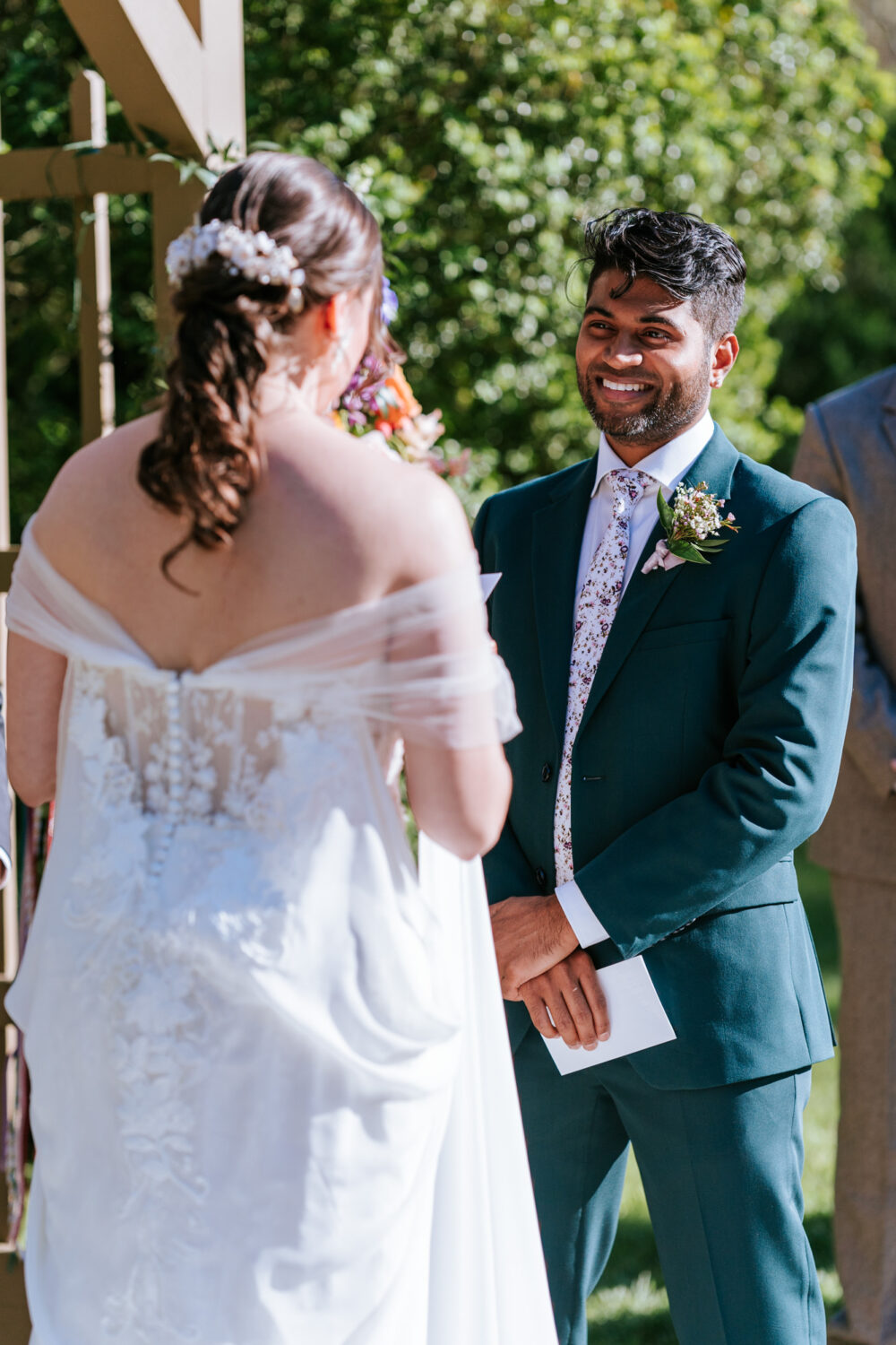 groom smiling while bride reads her vows