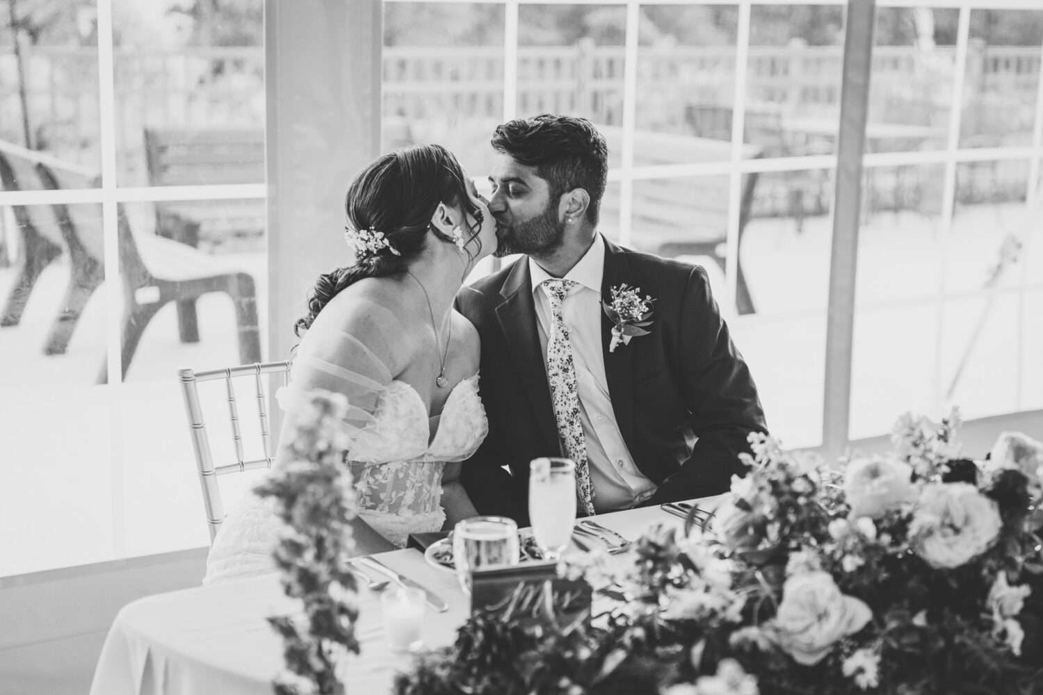 bride and groom sharing a kiss at their sweetheart table