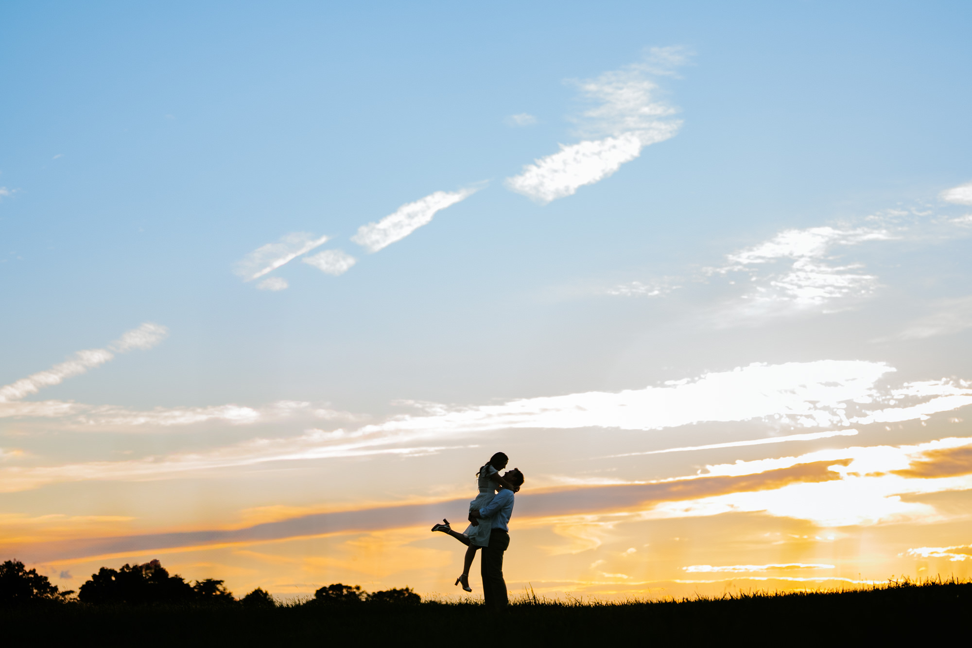 silhouette photograph of a groom lifting his bride in the air during their manassas battlefield park engagement session