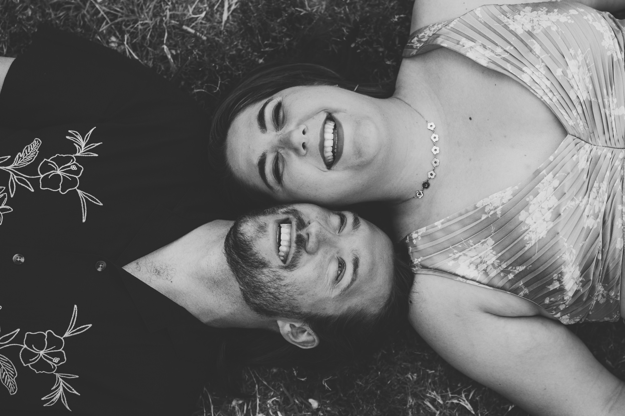 bride and groom laying down on the ground and laughing together