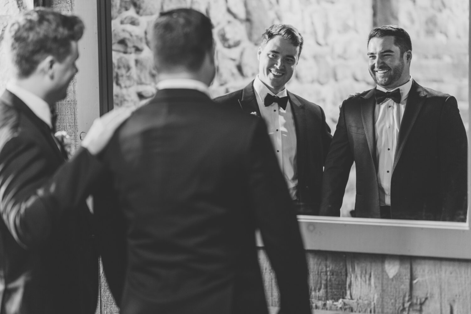 groom looking into the mirror with his groomsmen 