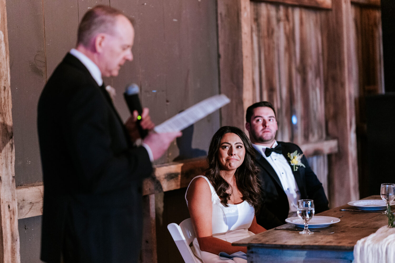 bride and groom reacting emotionally while listening to a welcoming speech by the bride's father