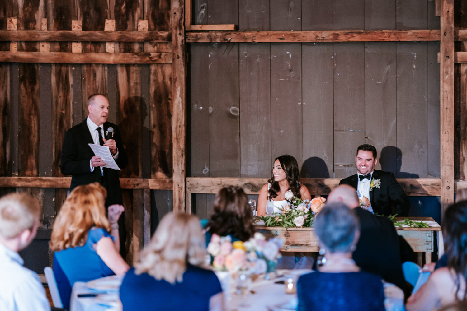 father of the bride laughing while giving a welcoming speech