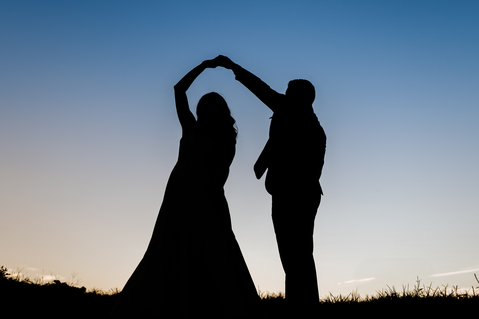 silhouette wedding photograph of the groom twirling his bride