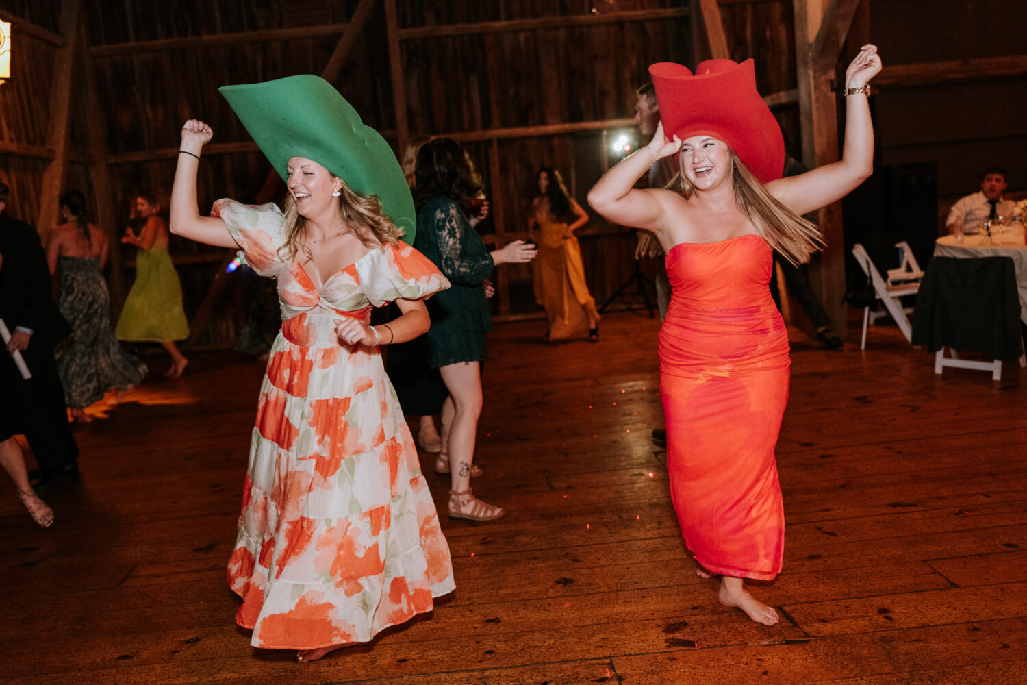 wedding guests wearing oversized hats and having fun on the dance floor