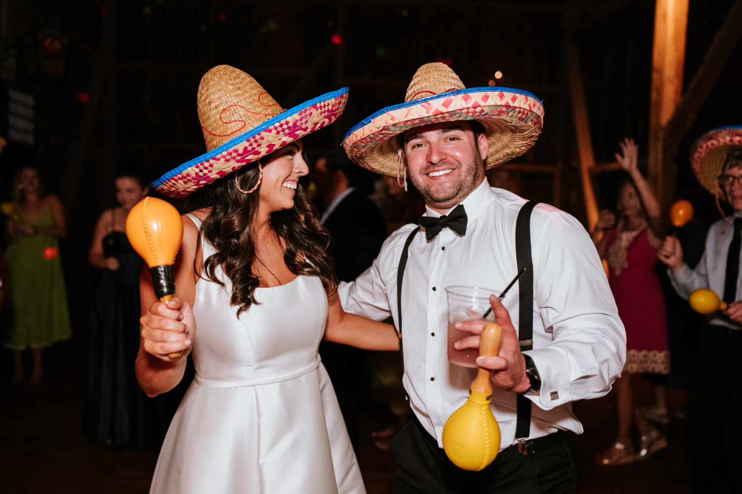 bride and groom having fun on the dance floor while wearing sombreros 