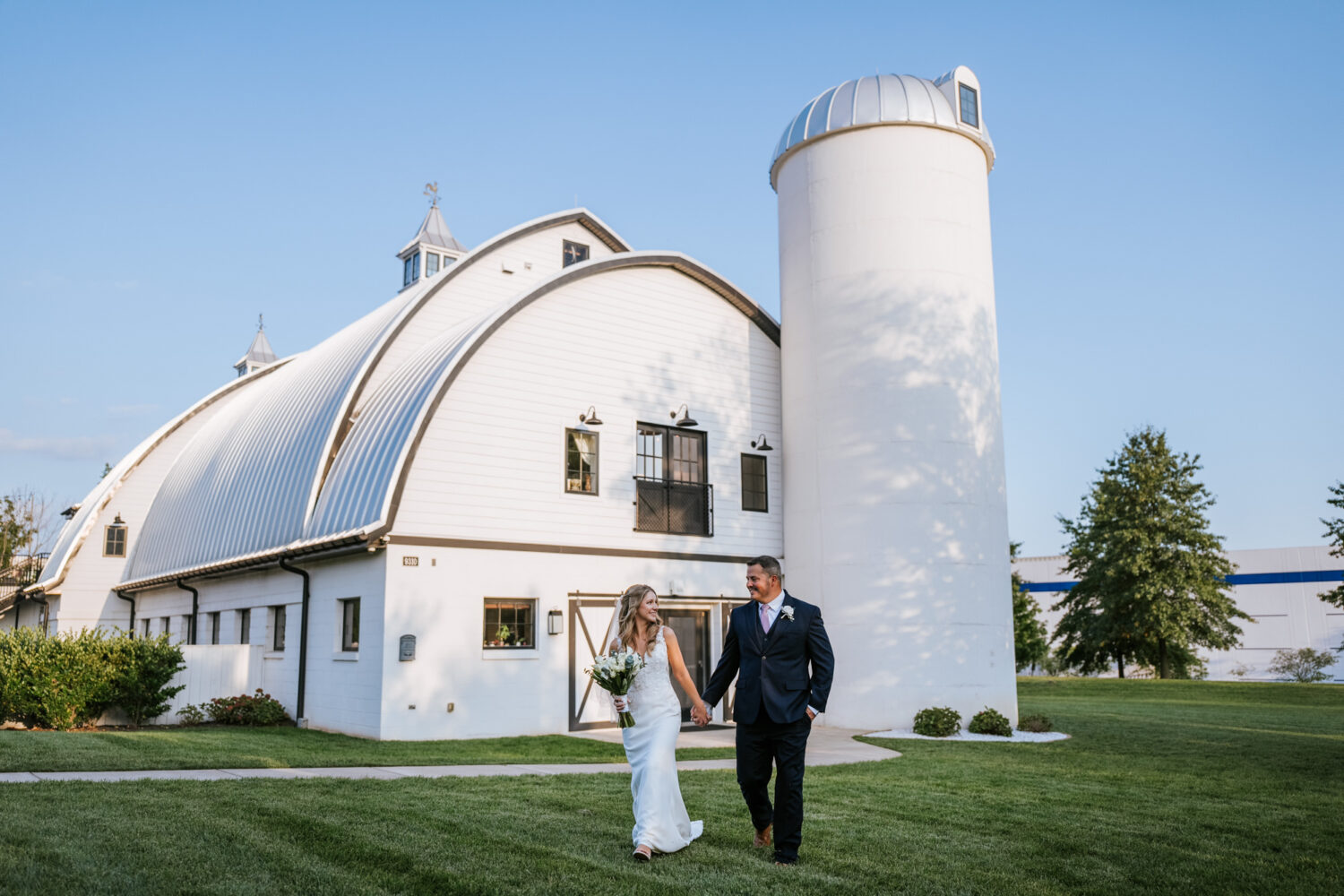 bride and groom walking in front of the sweeney barn wedding venue in manassas virginia